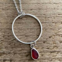 sea glass pendant with Red Sea glass on a circle of recycled silver hand made in Wales